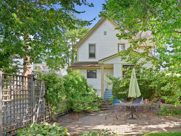 a view of a house with brick walls plants and large tree