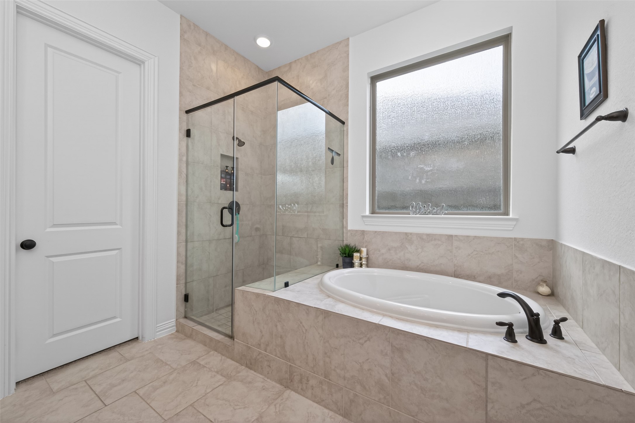 20802 Mirror Point Drive Cypress, TX 77433 - Photo 26 of 37 This bathroom features a modern design with a spacious glass-enclosed shower and a large soaking tub. The neutral tile work complements the sleek fixtures, and a frosted window provides natural light while maintaining privacy.