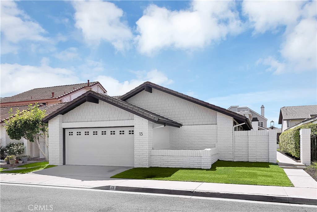 a view of a house with a yard plants and large tree