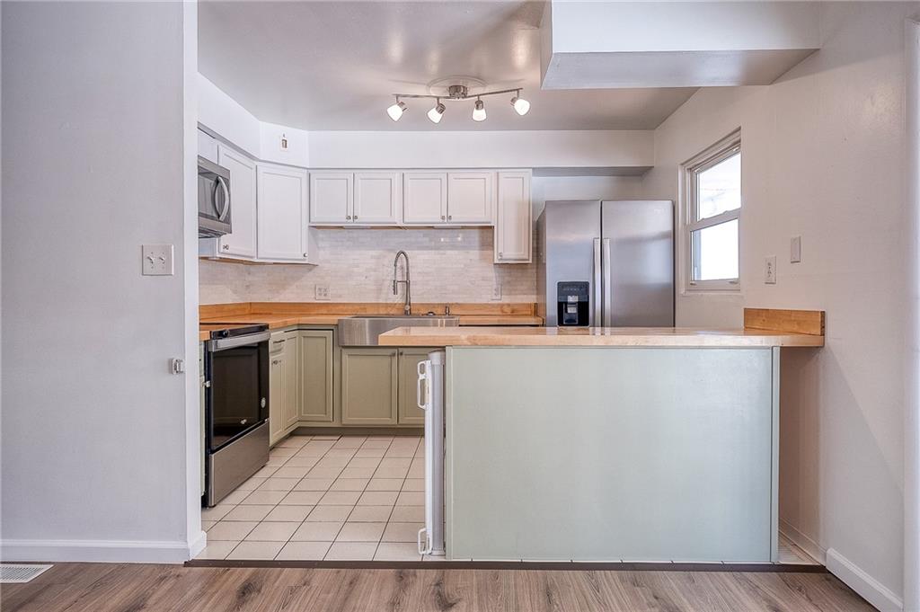 9871 Deerfield Drive Irwin, PA 15642 - Photo 4 of 35 a kitchen with stainless steel appliances a sink a stove a refrigerator cabinets and a dining table