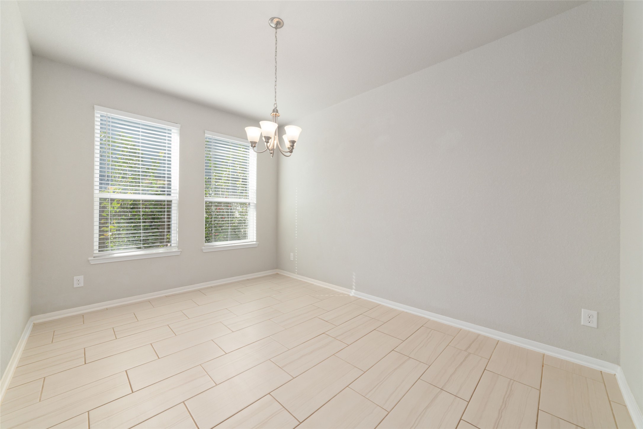 14838 Ruddy Duck Lane Houston, TX 77049 - Photo 13 of 33 Filled with natural light from two large windows, this dining room features light tile flooring, neutral tones, and a modern chandelier that adds a stylish touch.