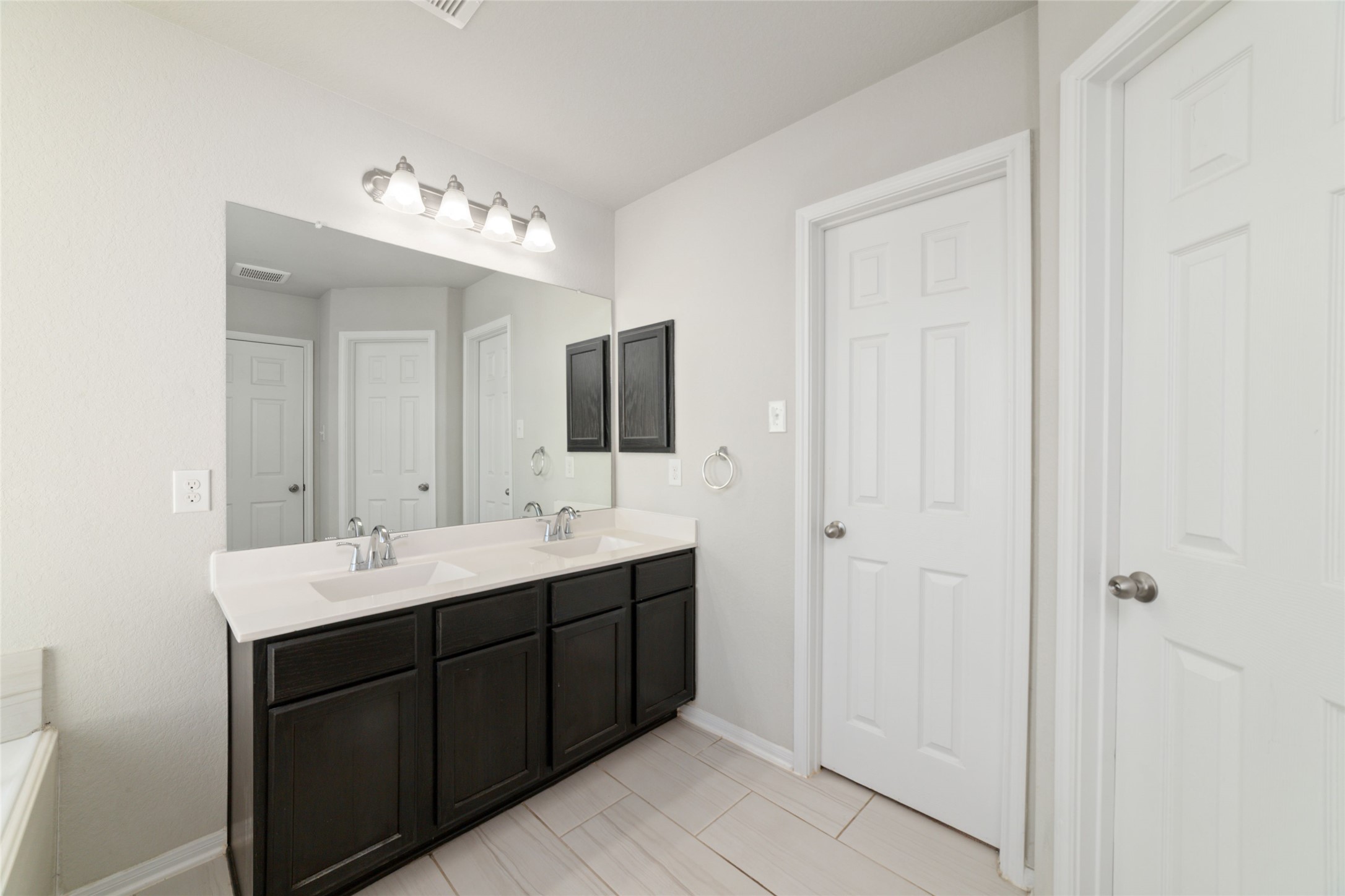 14838 Ruddy Duck Lane Houston, TX 77049 - Photo 22 of 33 The primary bathroom features a spacious double vanity with dark cabinetry, light countertops, and a large mirror, creating a bright and functional setup for everyday use.