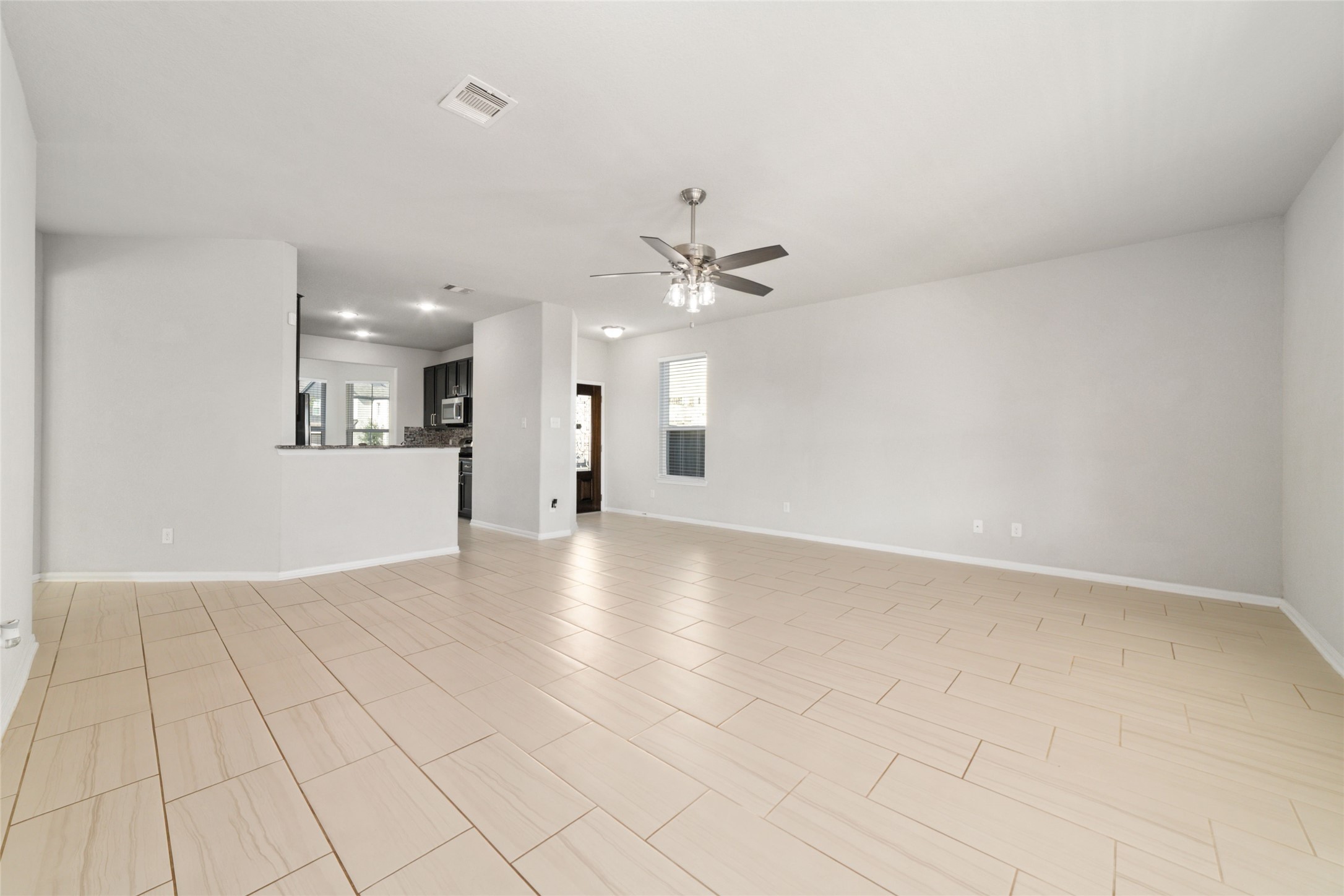 14838 Ruddy Duck Lane Houston, TX 77049 - Photo 6 of 33 This spacious living area features neutral tile flooring, a ceiling fan, and an open layout leading to a modern kitchen with stainless steel appliances, creating a bright and inviting atmosphere. Refrigerator is included!
