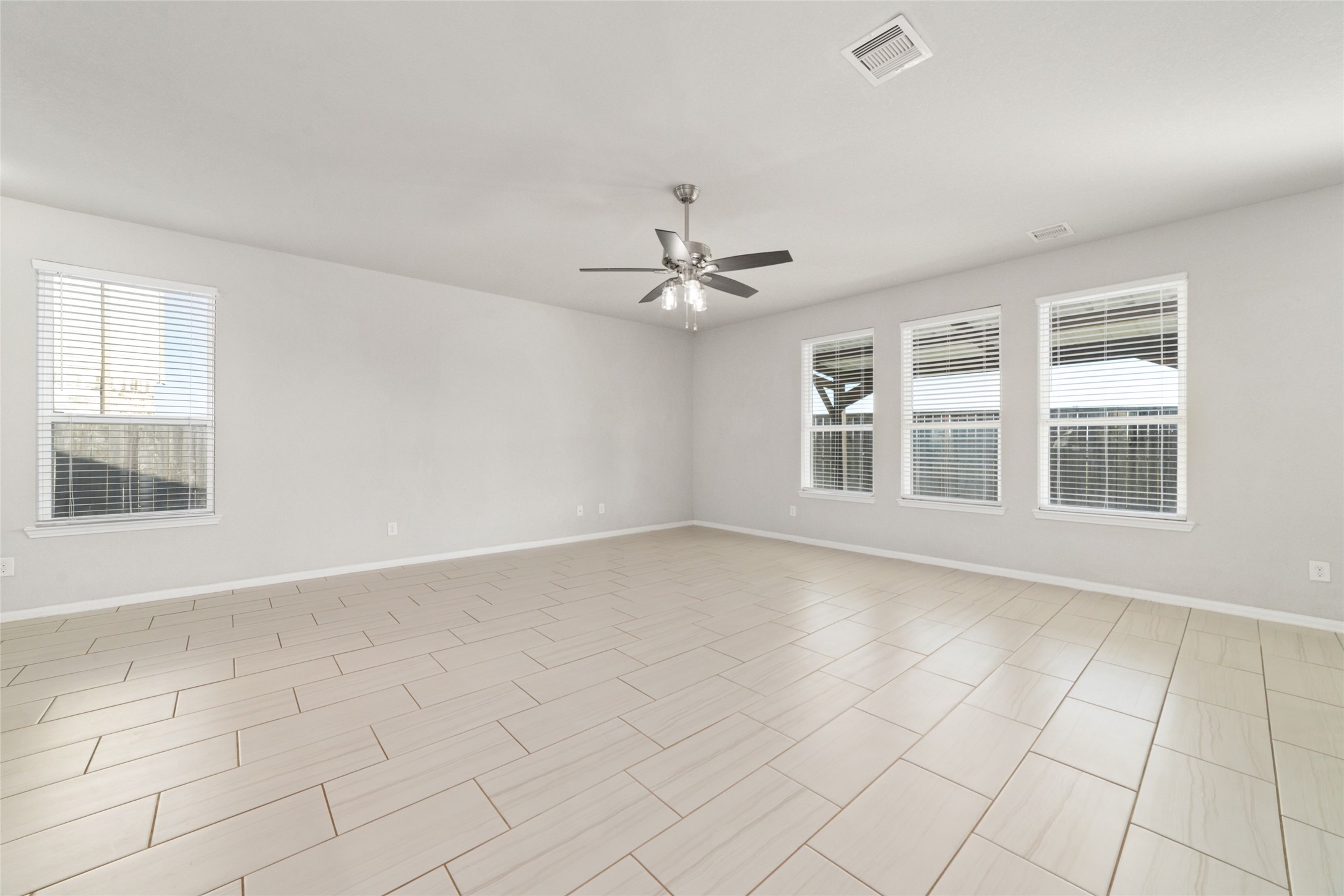 14838 Ruddy Duck Lane Houston, TX 77049 - Photo 7 of 33 This spacious living area features modern tile flooring, a ceiling fan, and ample natural light through multiple large windows, creating a bright and inviting atmosphere.