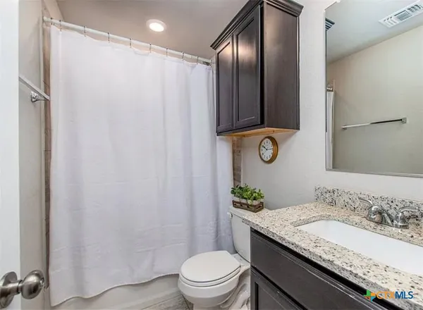 a bathroom with a granite countertop sink a toilet and shower