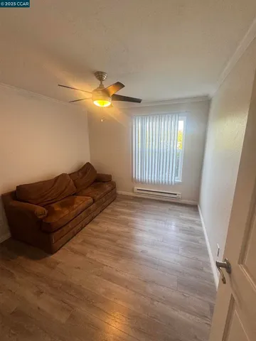 a view of empty room with wooden floor and fan