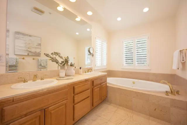 a spacious bathroom with a double vanity sink a bathtub and next to a window