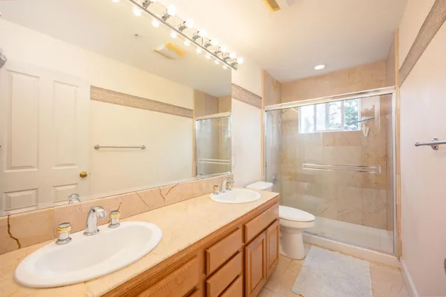a bathroom with a granite countertop sink a toilet and shower
