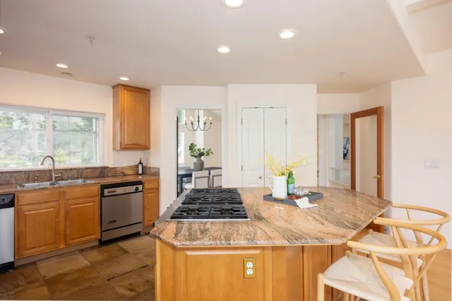 a kitchen with kitchen island granite countertop a sink and wooden cabinets
