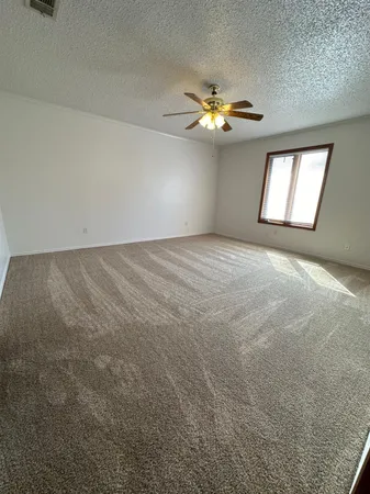 an empty room with windows and chandelier fan