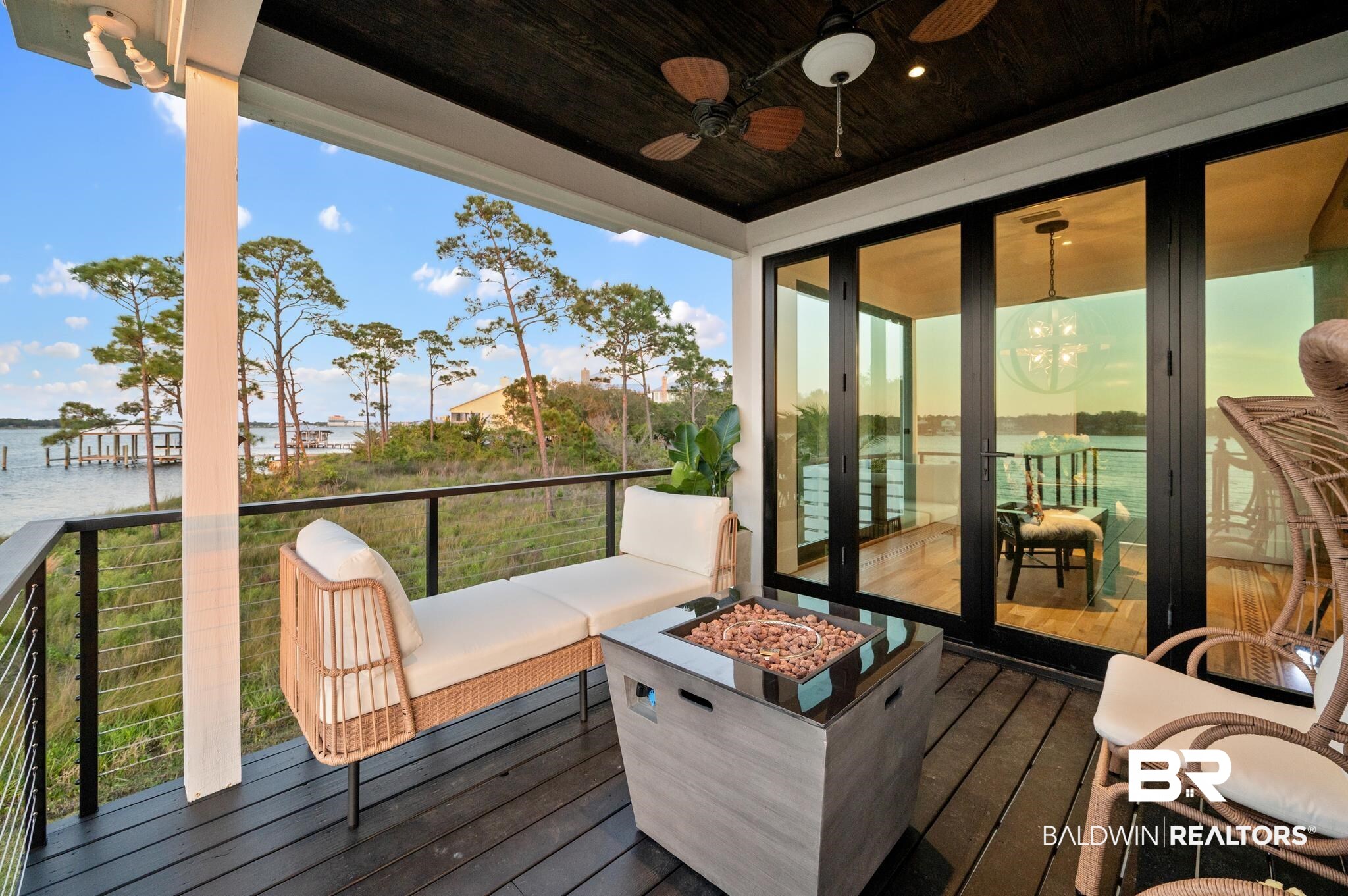 33349 River Road Orange Beach, AL 36561 - Photo 36 of 61 Covered balcony featuring wood-finish decking, black metal railings with horizontal cable infill, and a dark wood ceiling with integrated ceiling fans