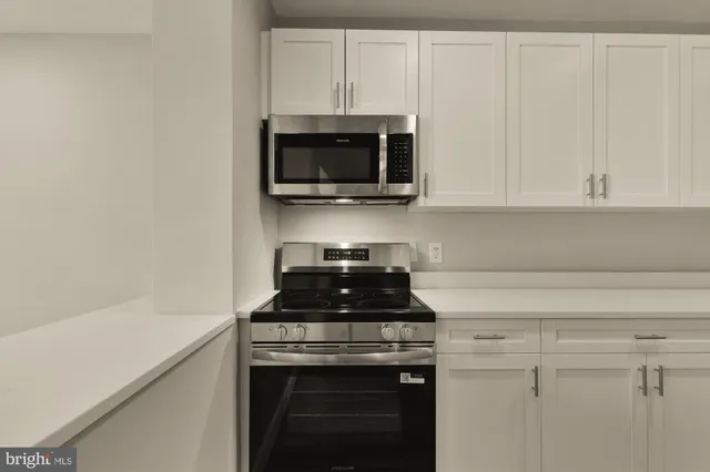 a kitchen with white cabinets and black appliances