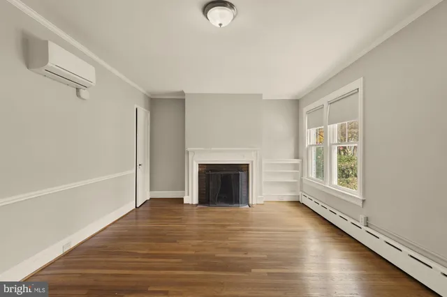 a view of a livingroom with wooden floor a fireplace and windows