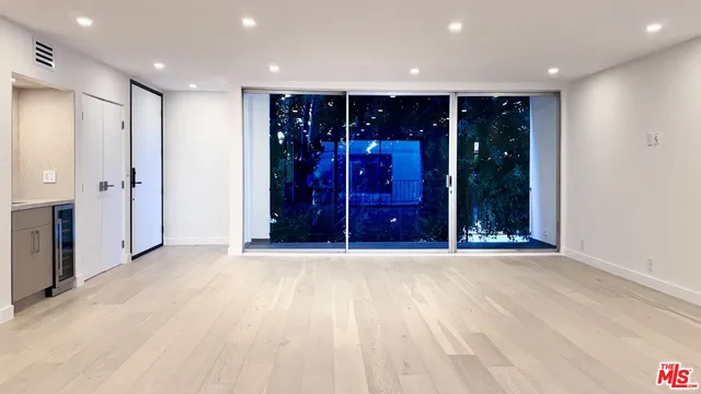 an empty room with wooden floor and glass door
