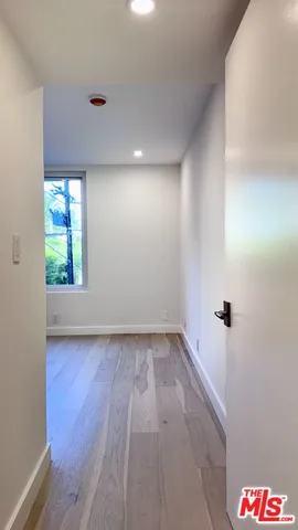 a view of a hallway with wooden floor and a bathroom