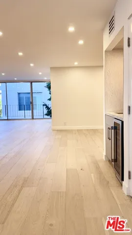 a view of an empty room with kitchen and a window