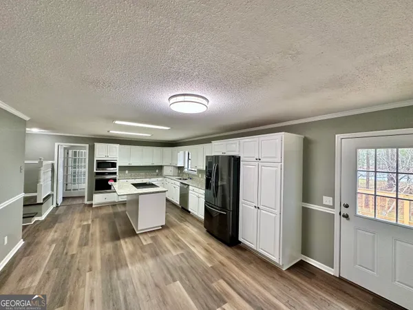 a kitchen with a refrigerator and wooden floor