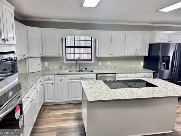 a kitchen with granite countertop a sink stove and cabinets