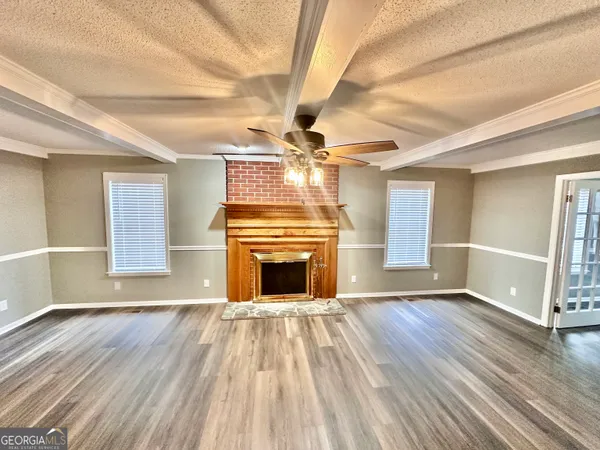 a view of an empty room with wooden floor fireplace and a window