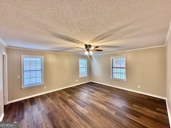 an empty room with wooden floor chandelier and windows