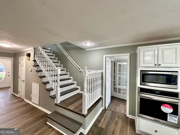 a view of an empty room with wooden floor and stairs
