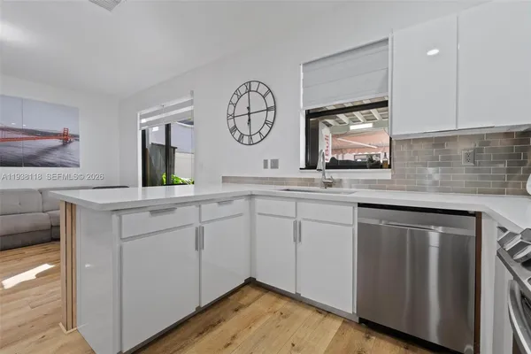 a kitchen with stainless steel appliances granite countertop a sink a stove and a wooden floors