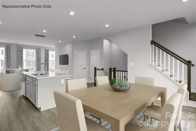 a kitchen with stainless steel appliances granite countertop a table chairs and white cabinets