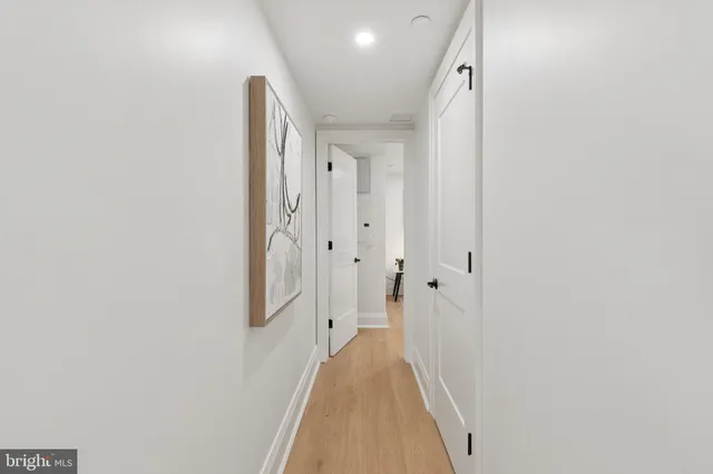 a view of a hallway with wooden floor and a bathroom