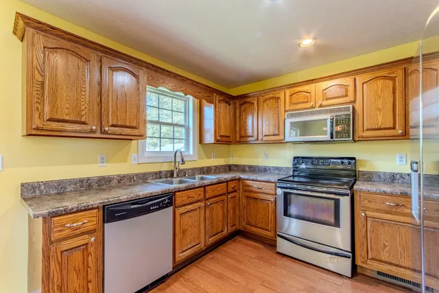 a large kitchen with stainless steel appliances granite countertop a stove a sink and a refrigerator