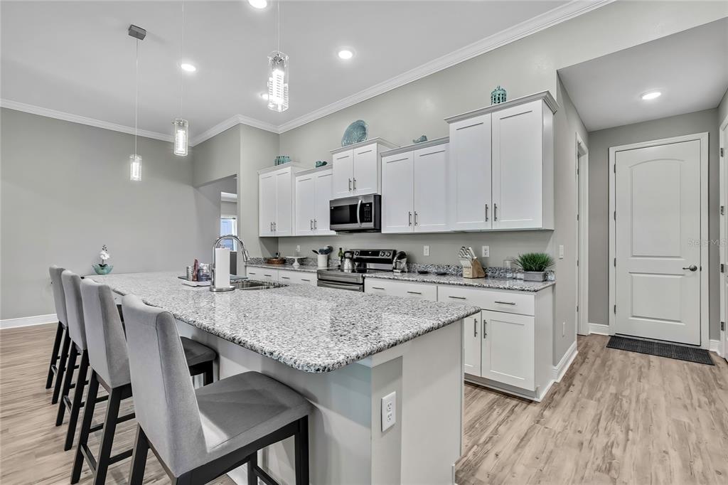 9504 Earthwind Court Weeki Wachee, FL 34613 - Photo 3 of 48 a kitchen with kitchen island granite countertop a stove a sink a refrigerator and white cabinets with wooden floor