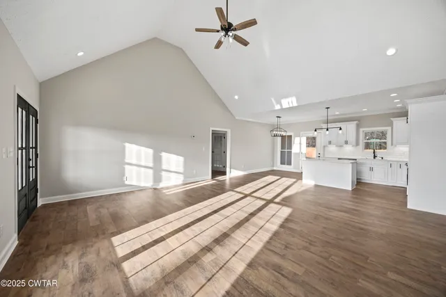 a view of a kitchen with kitchen island a window wooden floor and stainless steel appliances