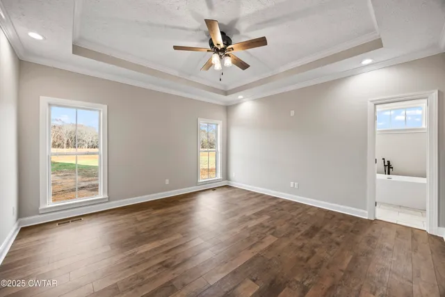 an empty room with wooden floor chandelier fan and windows