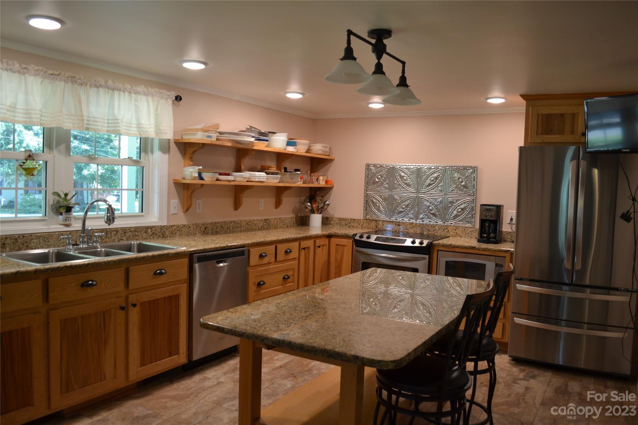 109 Tucker Street Locust, NC 28097 - Photo 8 of 13 a kitchen with granite countertop a table chairs stainless steel appliances and cabinets