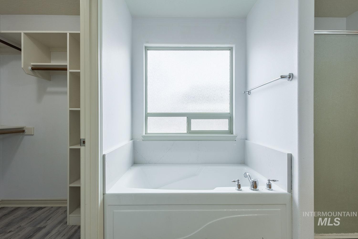 4227 North Rhodes Avenue Meridian, ID 83646 - Photo 11 of 27 Soaking tub with chrome fixtures, frosted window, and a built-in towel bar