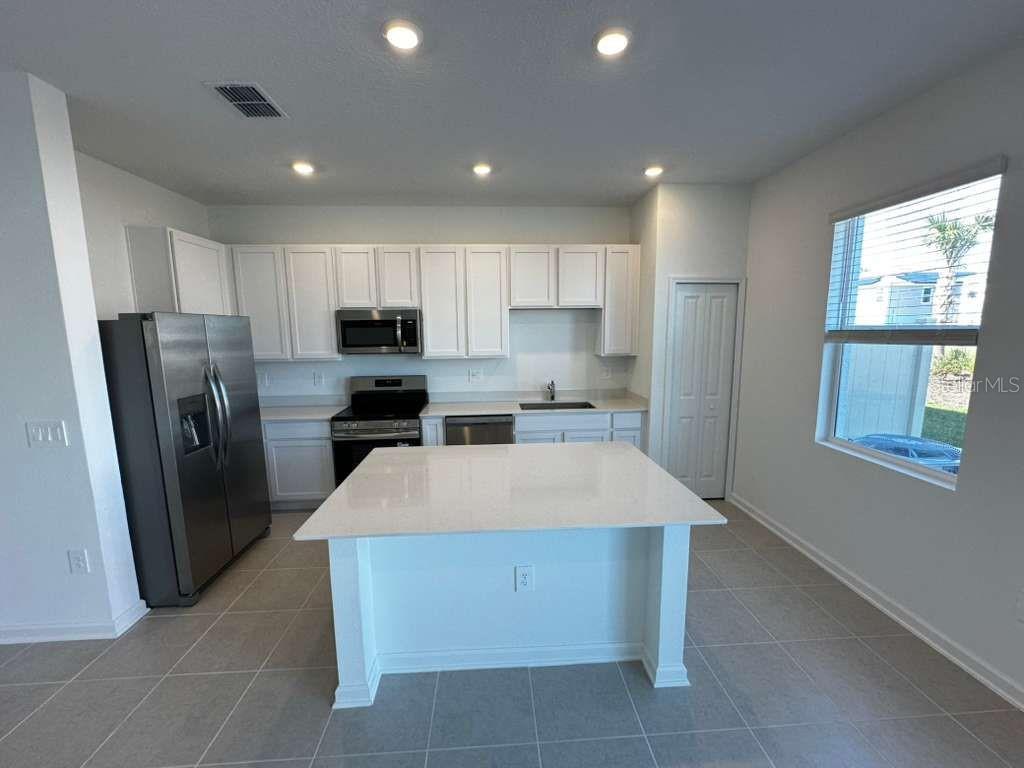 2713 Skyline Loop Kissimmee, FL 34758 - Photo 2 of 20 a large kitchen with stainless steel appliances kitchen island granite countertop a refrigerator a sink a stove and island