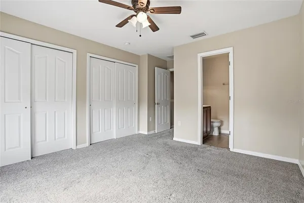 a view of an empty room and chandelier fan