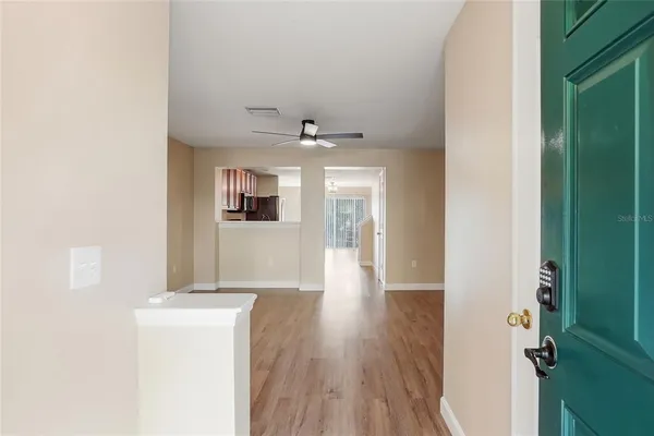 a view of a hallway with wooden floor and a kitchen