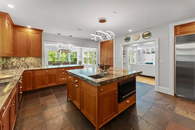 a kitchen with kitchen island granite countertop a stove and a sink