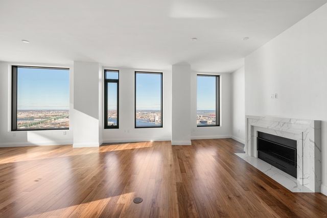 an empty room with wooden floor fireplace and windows