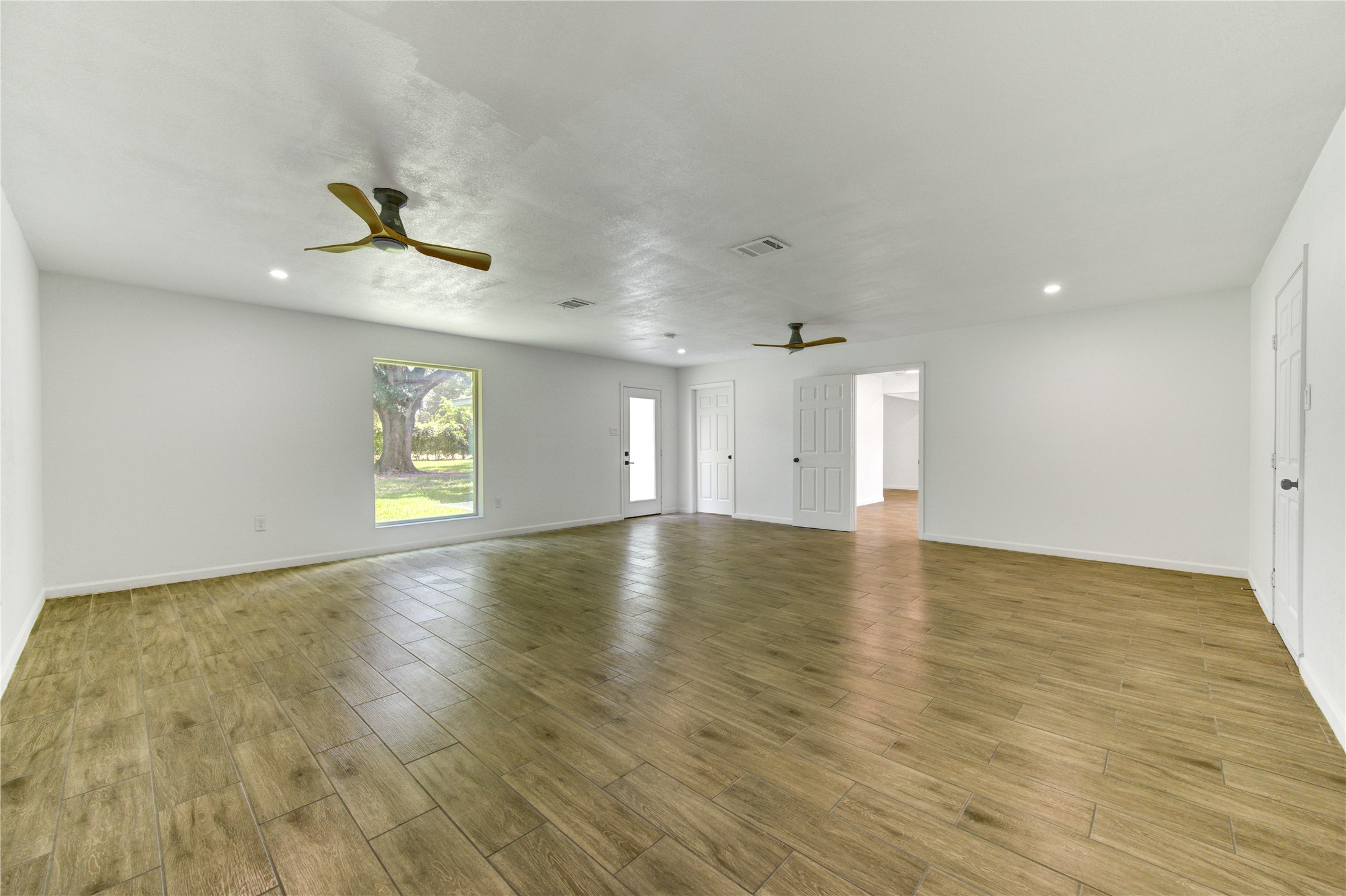 5411 Logston Lane Spring, TX 77389 - Photo 24 of 50 Spacious living area with elegant wood-style flooring, abundant natural light from a large window, and modern ceiling fans for comfort and style.