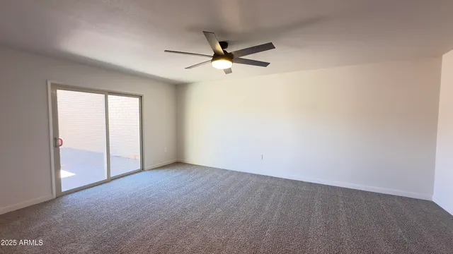 an empty room with a window and a fan