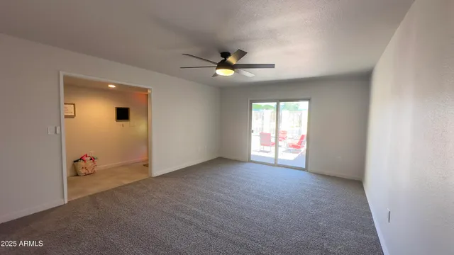 an empty room with chandelier fan and windows