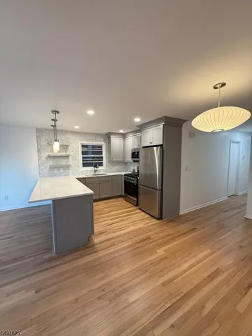 a large kitchen with stainless steel appliances kitchen island a large counter top and a refrigerator