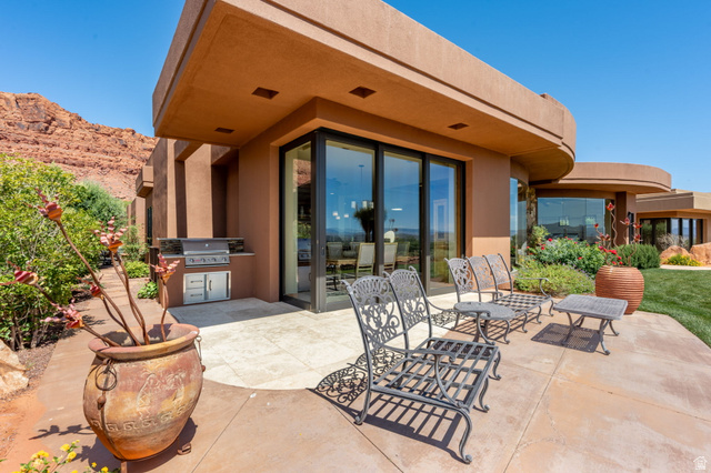 2331 West Entrada Trail, Unit 61 St. George, UT 84770 - Photo 58 of 69 Outdoor patio featuring a built-in outdoor kitchen with grill, expansive glass sliding doors, and a curved architectural design
