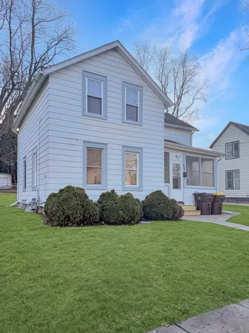 a brick house with a yard plants and big trees