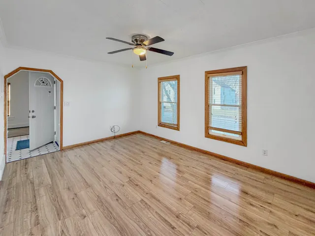 a view of empty room with wooden floor and fan