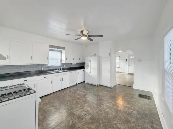 a large kitchen with cabinets appliances and a ceiling fan
