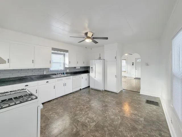 a large kitchen with cabinets appliances and a ceiling fan