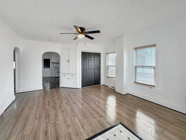 a view of empty room with wooden floor and fan