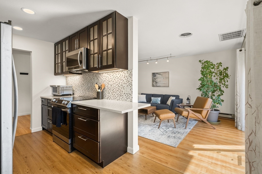 1206 Greendale Avenue, Unit 217 Needham, MA 02492 - Photo 10 of 33 a kitchen with stainless steel appliances granite countertop a stove top oven a sink dishwasher and a refrigerator with wooden floor